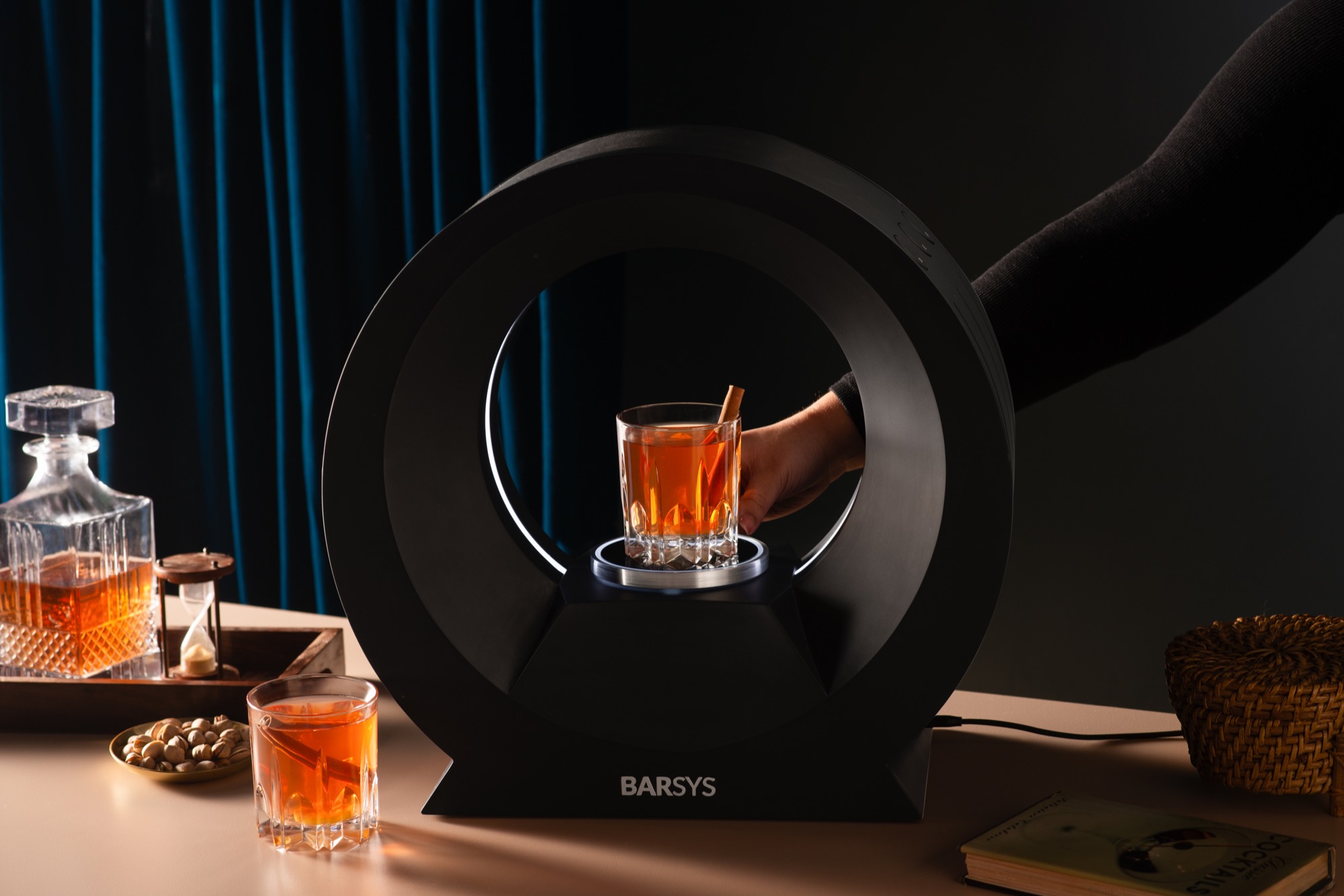 A finished old fashioned lit inside the 360's ring, a hand reaching in